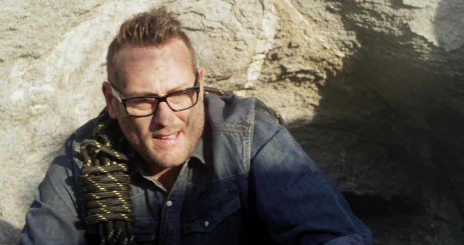 A man with short hair and glasses takes a breath in the sun