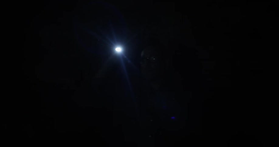 A man holds a flashlight at night