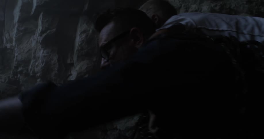 A young boy climbs onto the back of a rescuer who carries him out of a cave