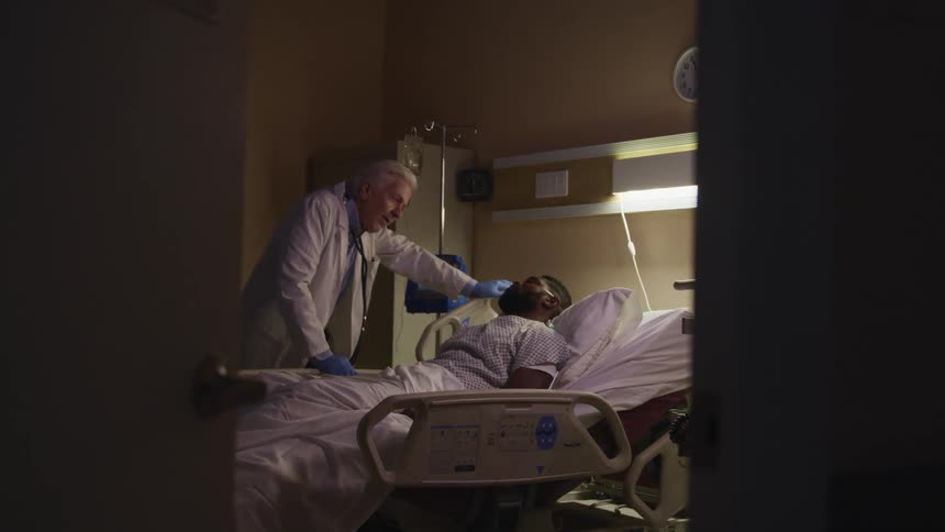 Doctor talking to a patient laying in a bed in a hospital room