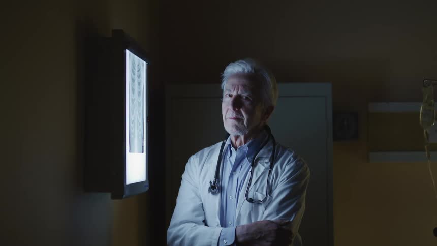Doctor stands next to x ray viewer box with x ray on it