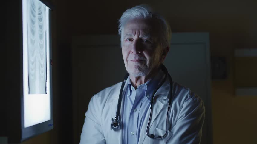 Doctor examines x ray in dimly lit office