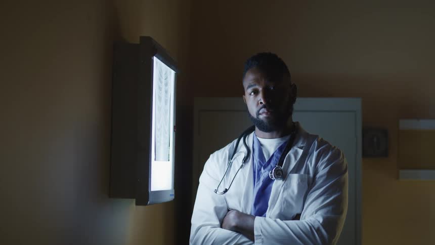 A doctor turns his gaze away from an xray to look into the camera