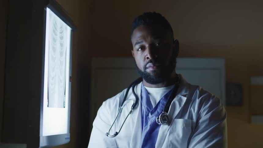 A doctor looking at an xray turns his head to look into the camera