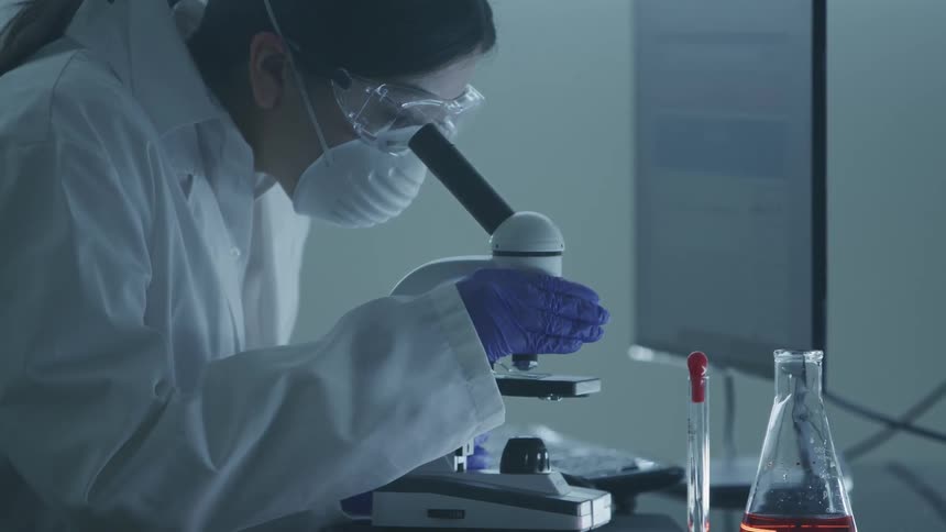 A woman using a microscope in a lab