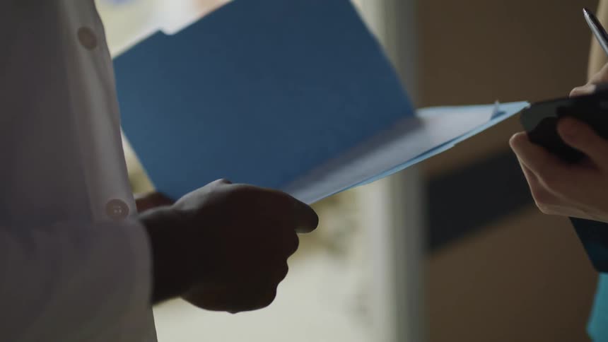 A doctor and nurse talk outside a patient room