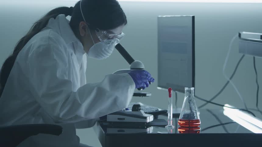 A woman looks through a microscope