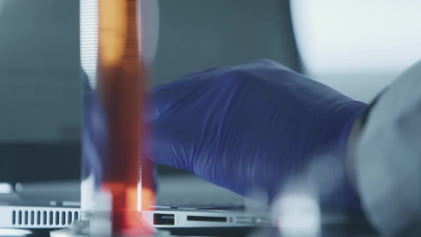 A person in a lab types on a laptop