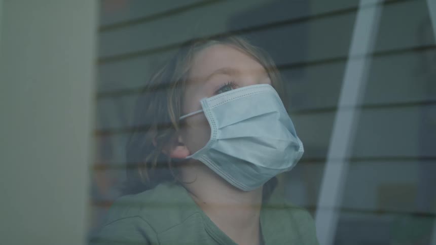 Young blonde boy with a blue mask looks up out the window