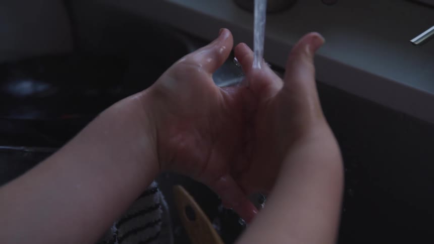 Child puts his hands under a tap and washes his hands with water