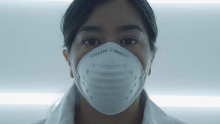 Close up of a womans face wearing a white face mask