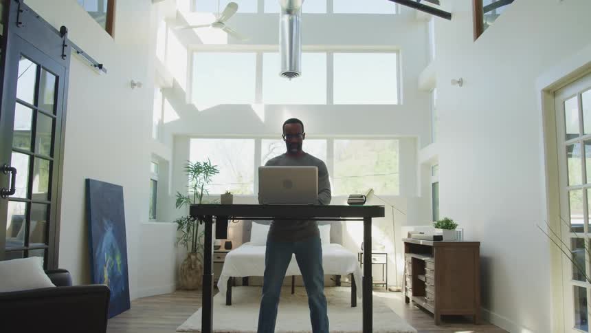 A black male working on his laptop in a house