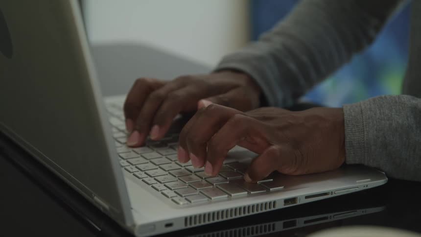 A person sits at a desk typing on a laptop