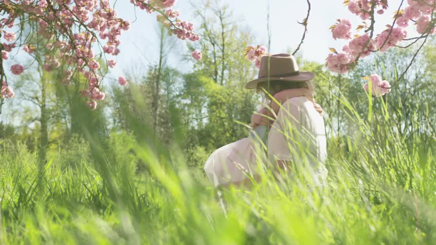 A little girl hugs her mom outside under blooming trees