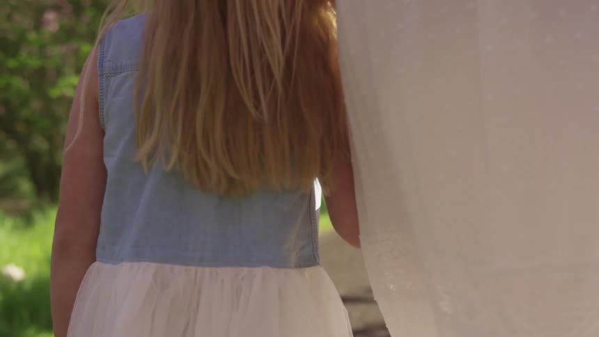 A child and woman walk in the yard together