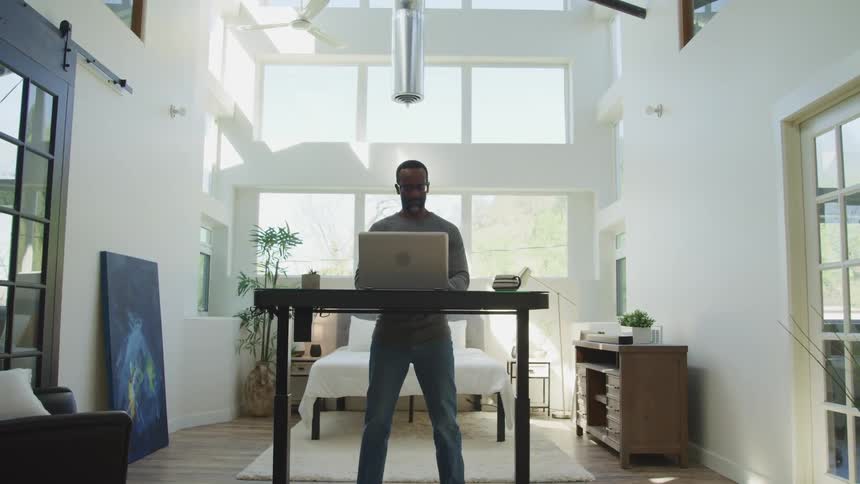 A man is using a laptop on his standing desk