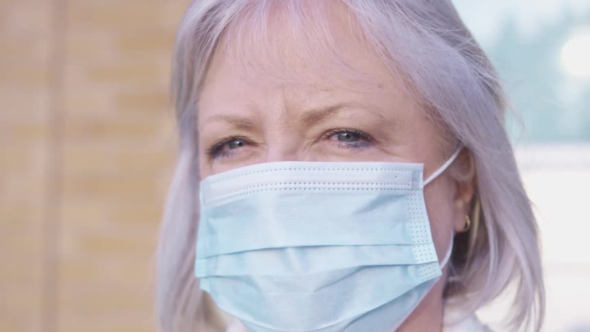 A woman is outside wearing a face mask