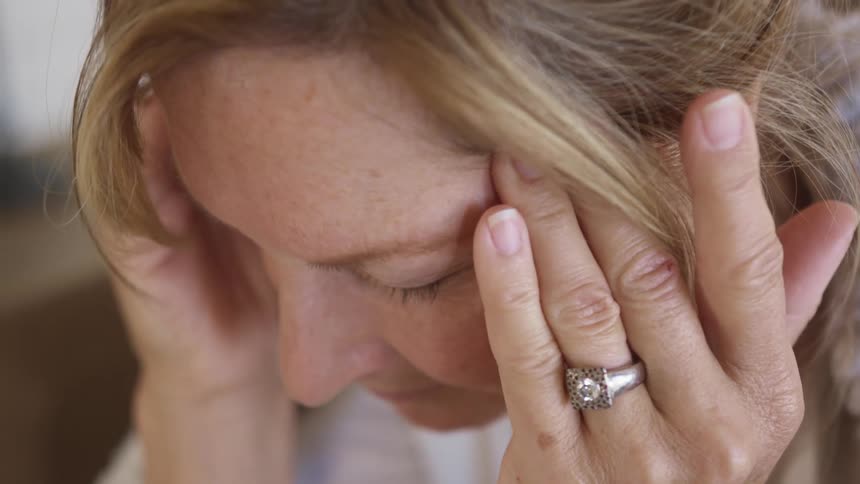 A woman with a ring rubbing her temples with her fingers