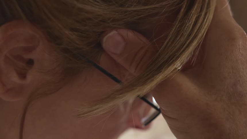 A woman rubbing her head with her hand