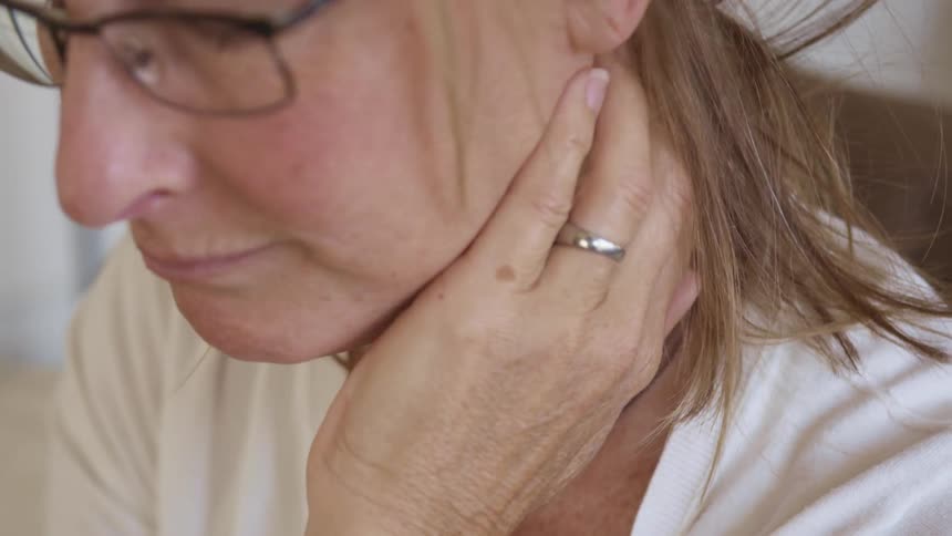 A woman is rubbing her neck