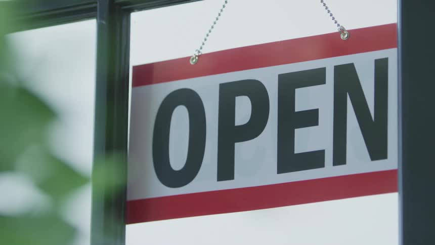 A person flips the open sign
