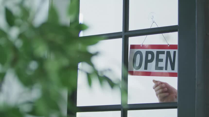 An employee flips a sign on a store door