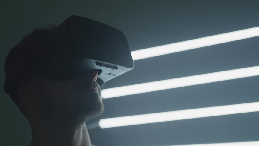 A man wearing a virtual reality headset turns his head from side to side as he looks around his virtual environment