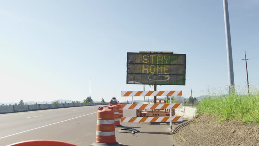 A digital street sign on the side of a freeway on a sunny day