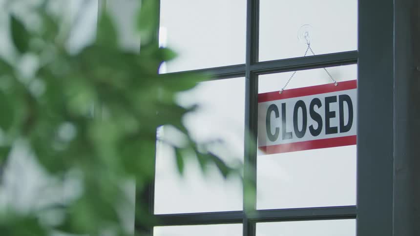 A hanging sign in a window that indicates the business is open until it is flipped over to show closed