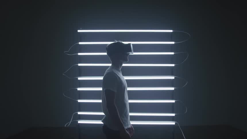 Man wears vr goggles and looks around in room lit by light array