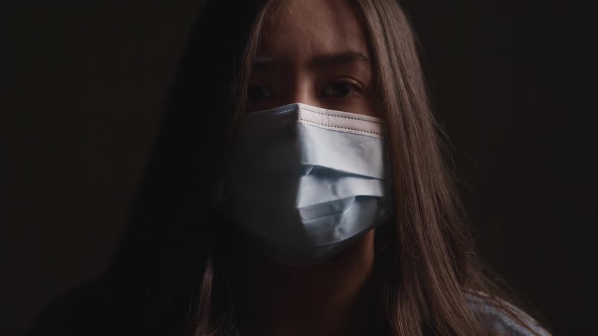 A teenage girl with a mask on raisers her eyes