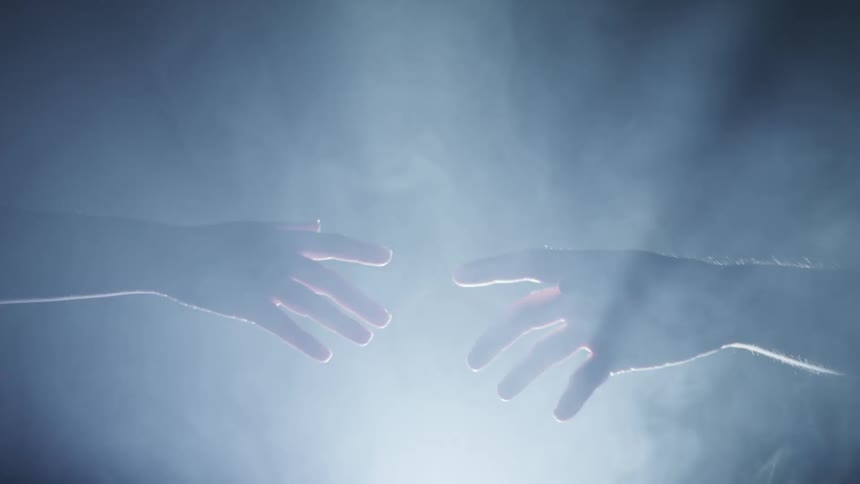 Two hands reaching out and touching while lights strobe