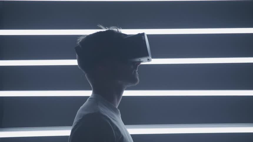 Man wearing a virtual reality set in a futuristic room