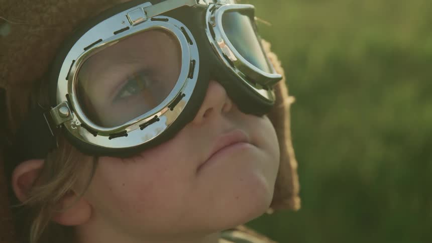A little boy stands outside with goggles on