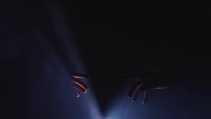 Two people reach forward and touch fingers as lights flash
