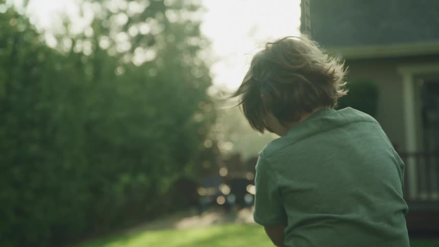 A young boy swings in his back yard