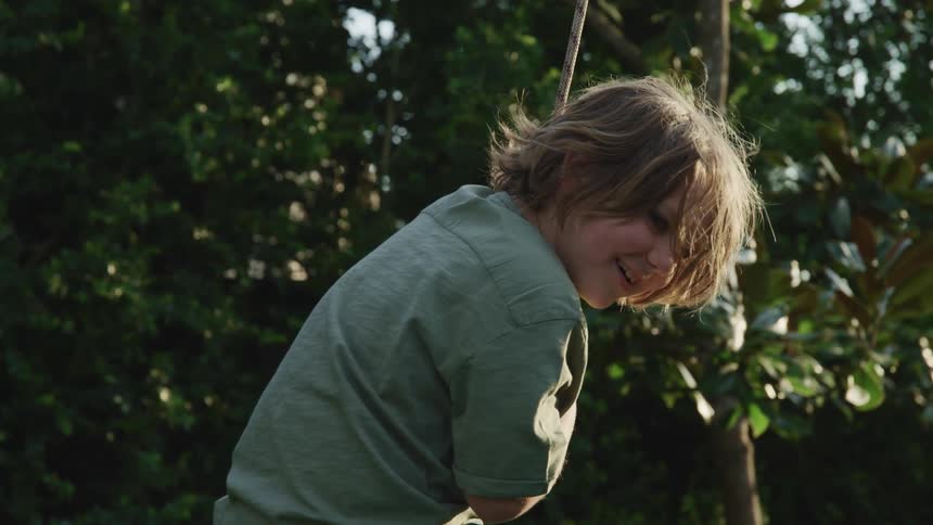A little boy swinging on a rope swing