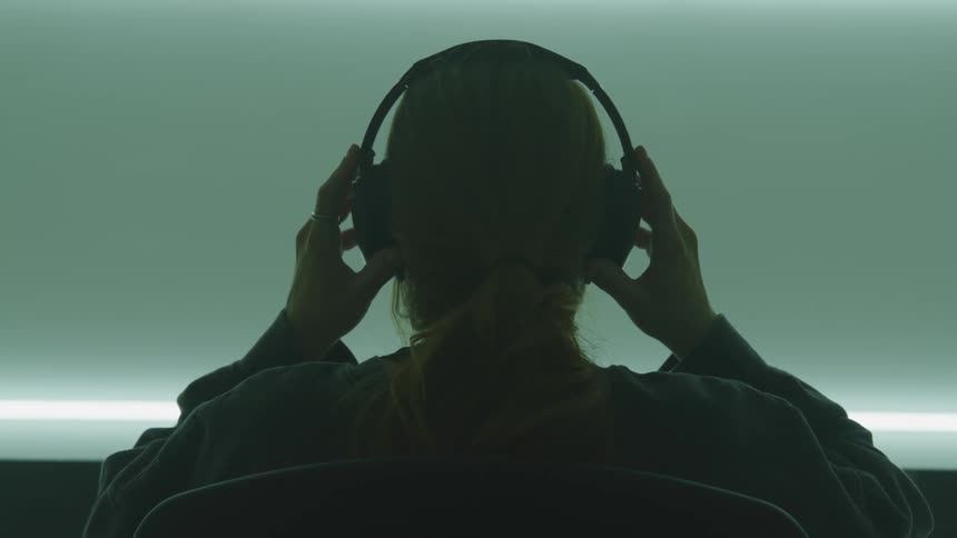 Woman with a ponytail and a sweater wears black headphones