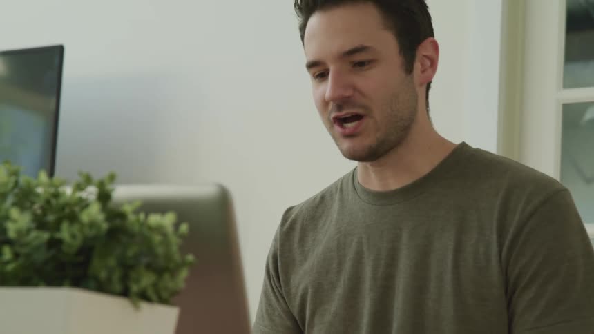 A man sitting at home video chats with someone on a computer