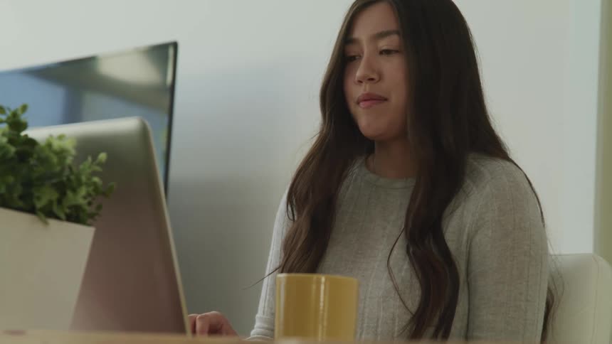 A teenage girl video chats on her computer while at home