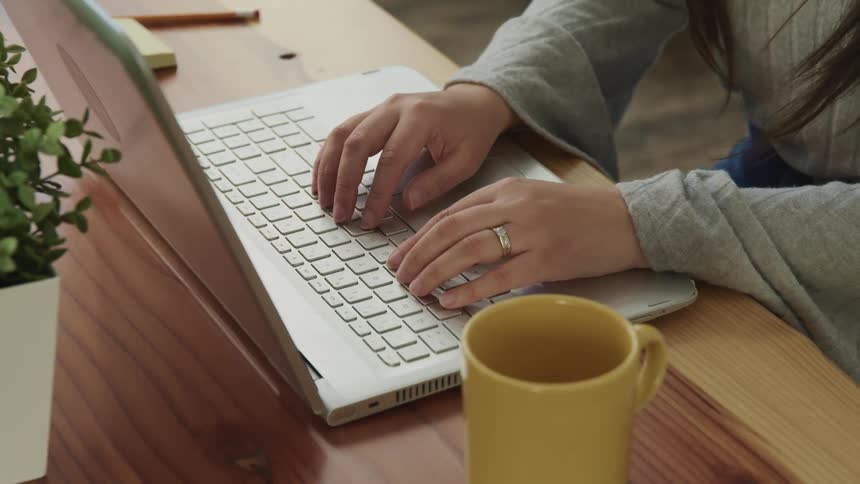 Female types on keyboard of laptop while sitting at desk