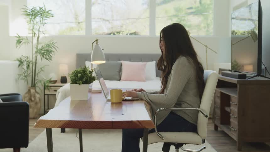 A teenager works on her laptop at home