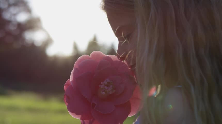 A little girl smelling a flower outside