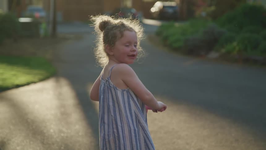 A little girl plays on a scooter in a neighborhood