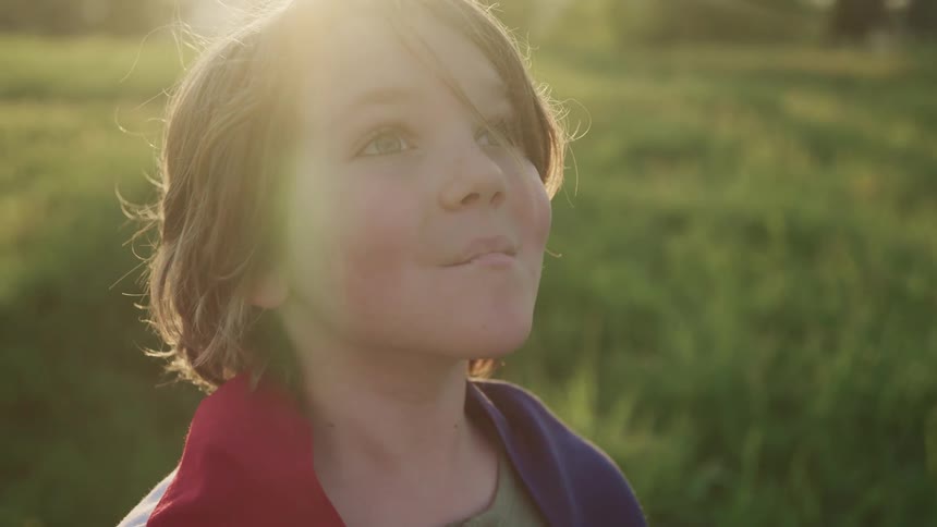 Young boy standing in a field looking up to the sky in wonder
