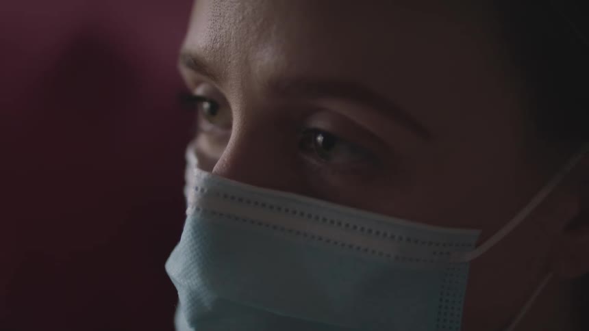 Close up of a young woman face wearing a blue face mask indoors