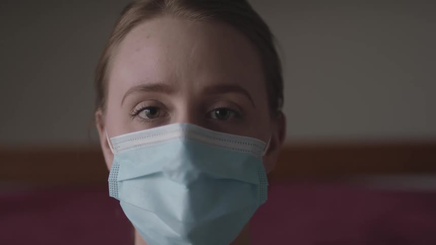 A woman wearing a mask blinks