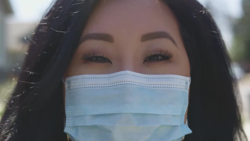 Close up of a womans face wearing a blue face mask outdoors