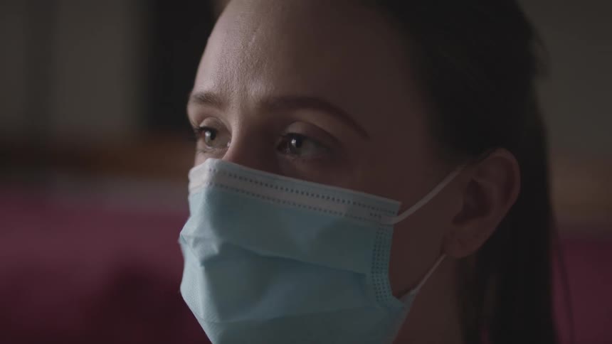 A woman with a mask staring off into the distance