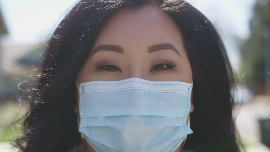 Close up of a womans face wearing a blue face mask
